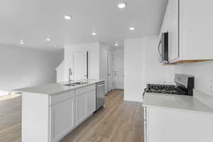 Kitchen with white cabinets, a center island with sink, dark wood finished floors, stainless steel appliances, and recessed lighting