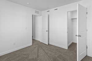 Unfurnished bedroom featuring dark carpet and a spacious closet