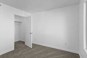 Unfurnished bedroom featuring dark colored carpet and a walk in closet