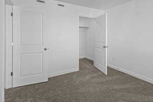 Unfurnished bedroom featuring dark carpet and a spacious closet