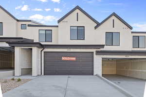 View of front of home featuring stucco siding, an attached garage, and driveway