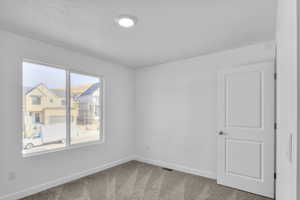 Empty room featuring baseboards and light carpet