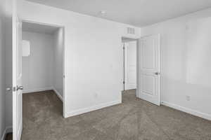 Unfurnished bedroom featuring dark carpet and a walk in closet