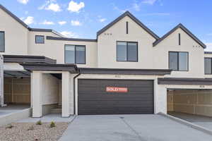 View of front facade with stucco siding, an attached garage, and driveway