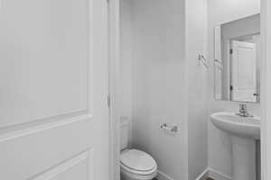 Half bath featuring toilet and baseboards