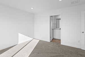 Unfurnished bedroom featuring light carpet, recessed lighting, and ensuite bathroom
