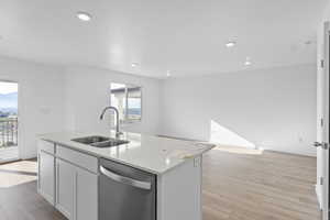 Kitchen featuring stainless steel dishwasher, light wood-style floors, white cabinetry, a center island with sink, and recessed lighting