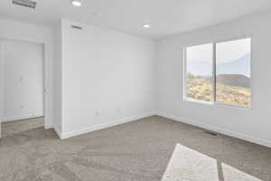 Spare room with a mountain view, light carpet, and recessed lighting
