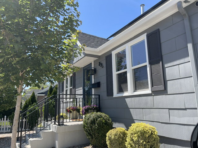 Shingle-sided exterior in a neutral gray tone with white trim and dark louvered shutters