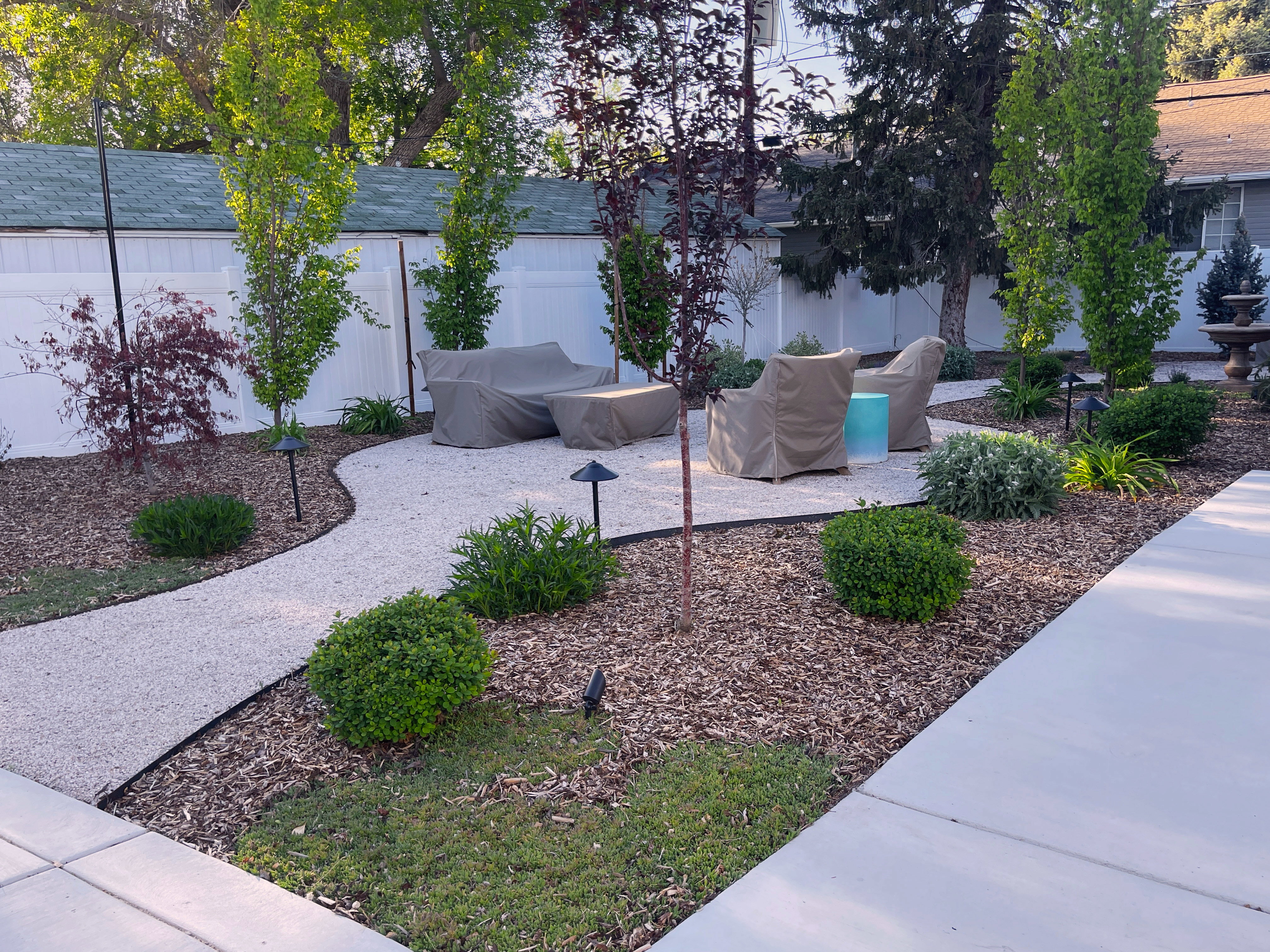Landscaped outdoor area featuring a gravel patio, defined by a curving gravel path and mulch beds