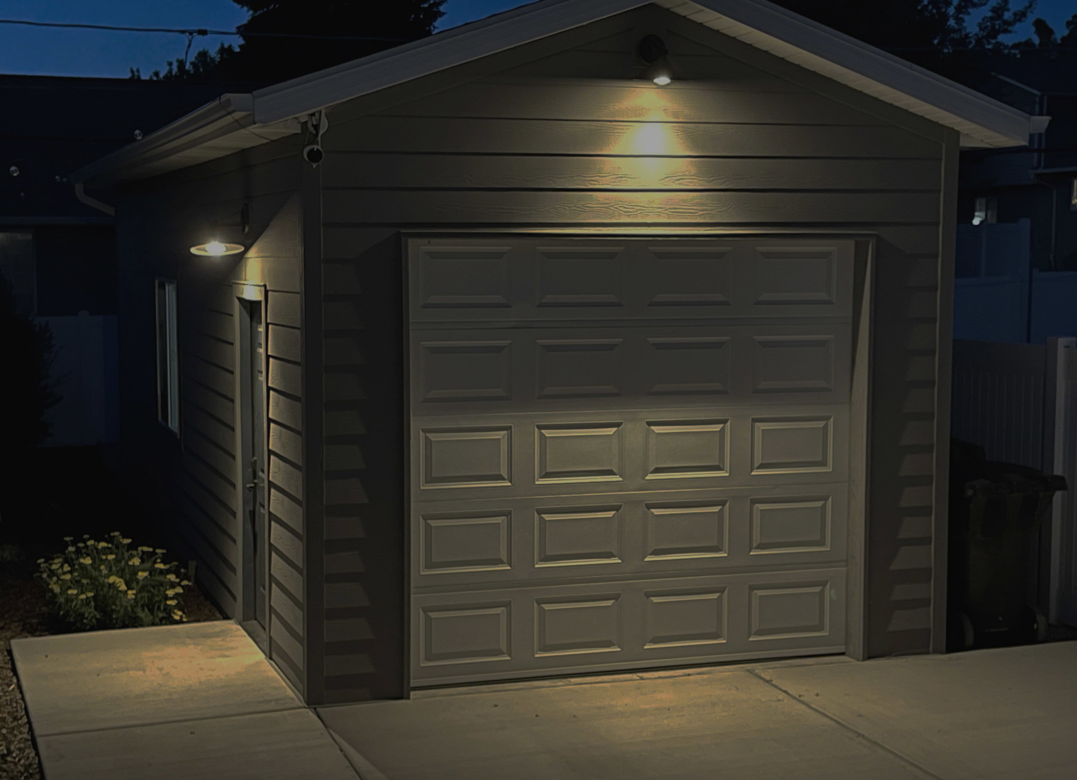 Detached garage with horizontal siding, a paneled overhead door, and a side entry door