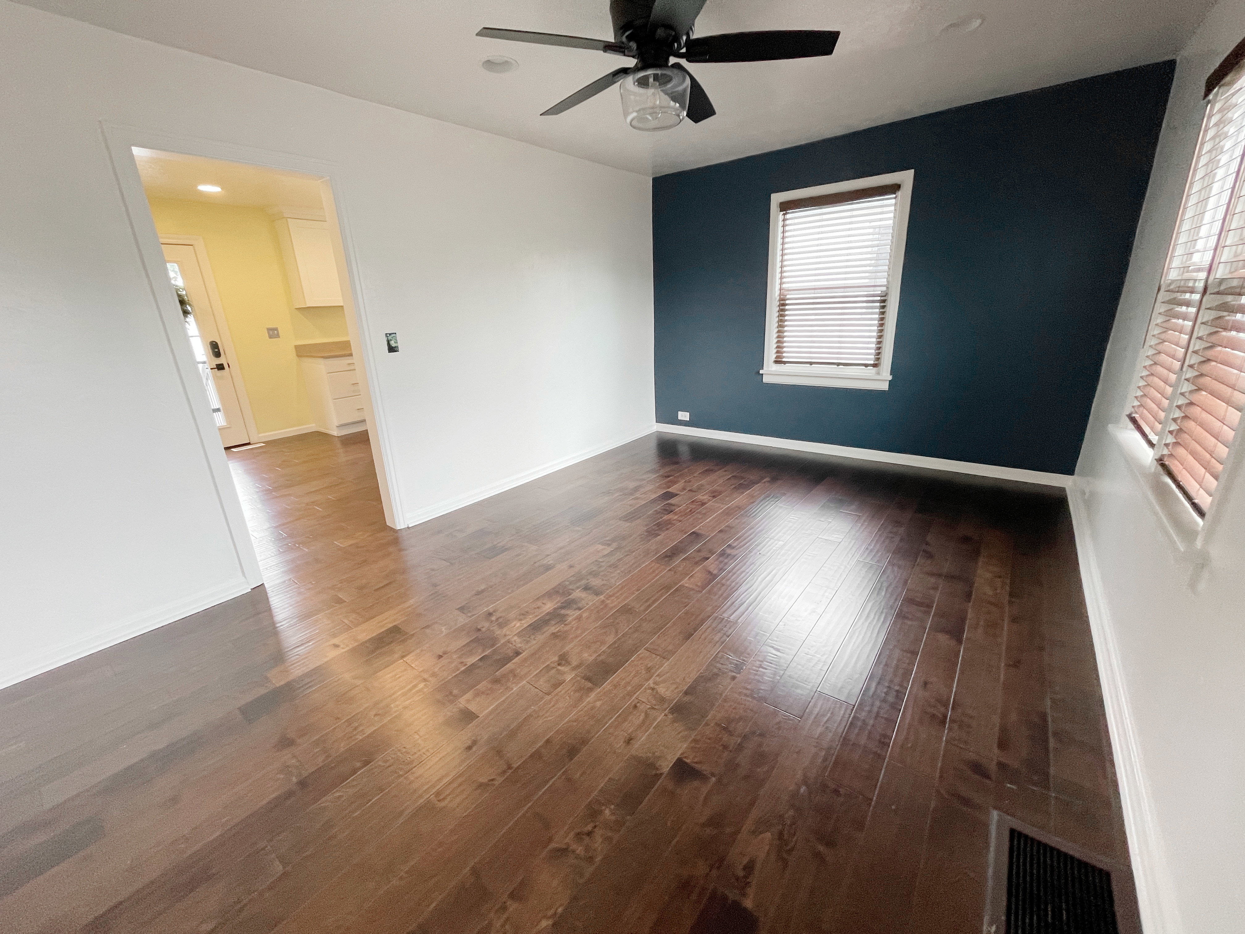 Rich wood-finish flooring throughout, complemented by a deep blue accent wall