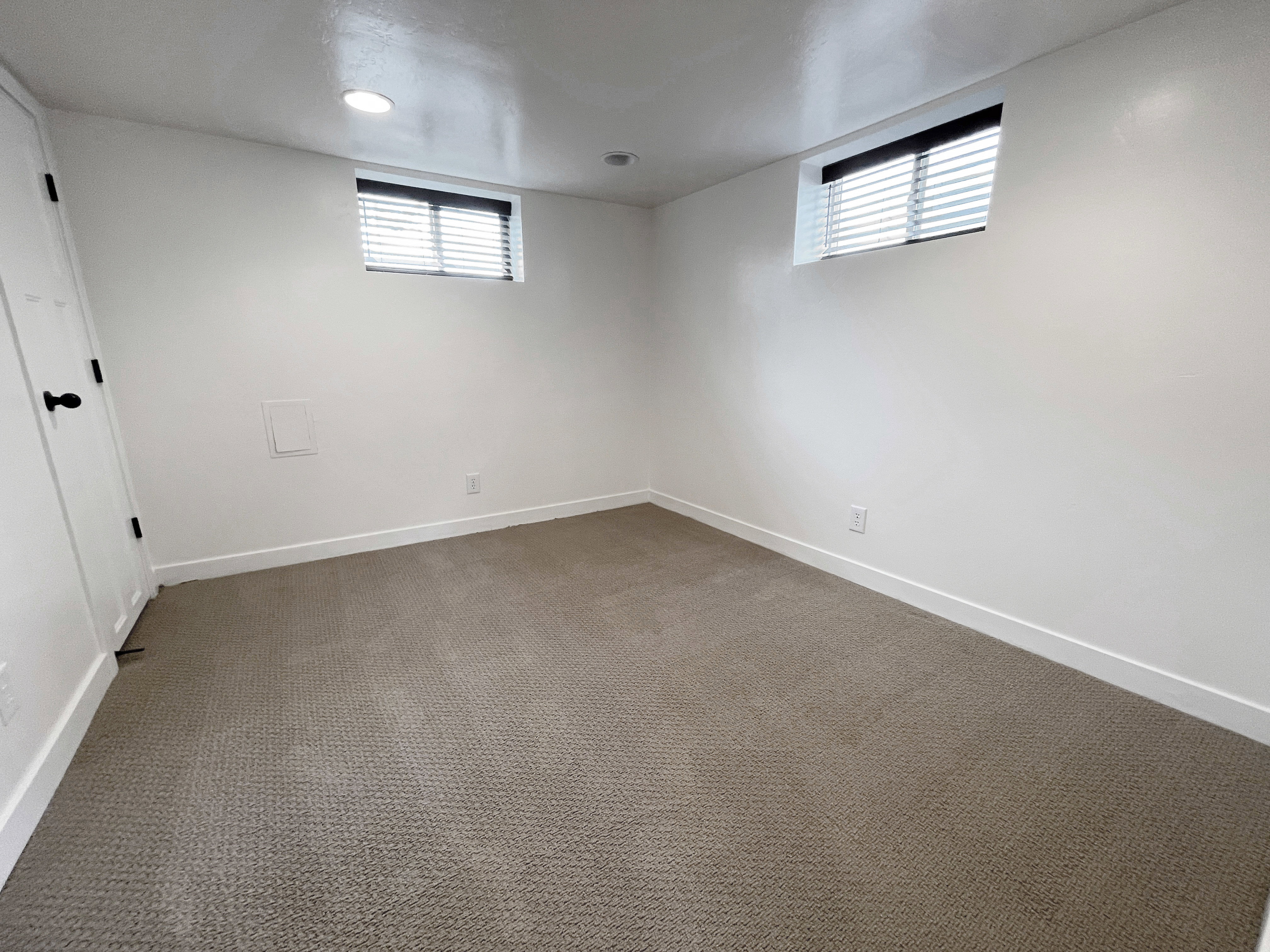 Carpeted room featuring recessed lighting, white walls, and two windows with blinds