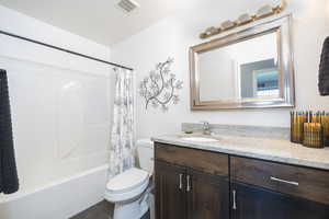 Full bathroom featuring vanity, shower / tub combo, and dark tile patterned floors