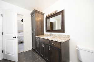 Bathroom with vanity, ensuite bath, dark tile patterned flooring, and a ceiling fan