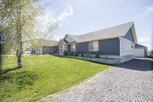 View of front of house featuring a shingled roof, a front yard, an outdoor structure, and a detached garage