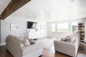 Living area featuring dark wood-type flooring, recessed lighting, and beamed ceiling