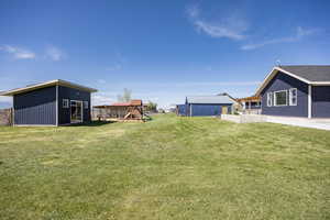 View of green lawn featuring an outdoor structure and a playground