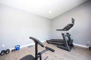 Exercise room with light wood-type flooring and baseboards
