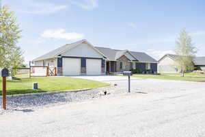View of front of property with driveway, an attached garage, stone siding, and a gate