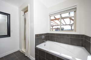 Bathroom featuring a stall shower, a bath, and dark tile patterned floors
