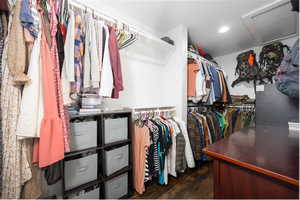 Walk in closet featuring attic access and dark wood finished floors