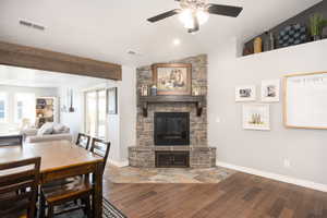 Dining room with ceiling fan, hardwood / wood-style floors, vaulted ceiling, healthy amount of natural light, and a stone fireplace