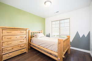 Bedroom with dark wood finished floors and baseboards