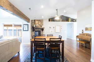 Dining space with dark wood-style flooring, a fireplace, ceiling fan, and vaulted ceiling