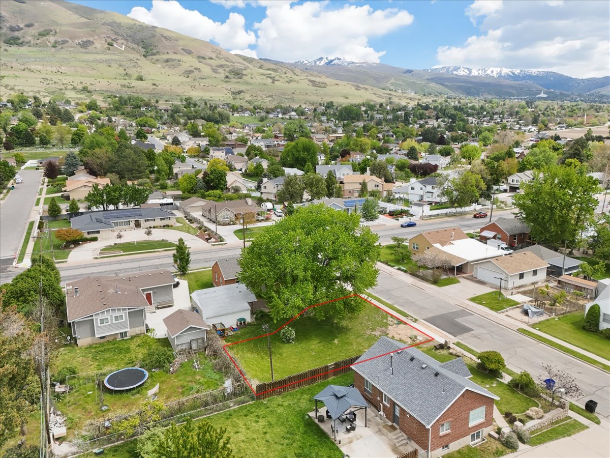 Aerial view of residential area featuring property boundaries highlighted and a mountainous background