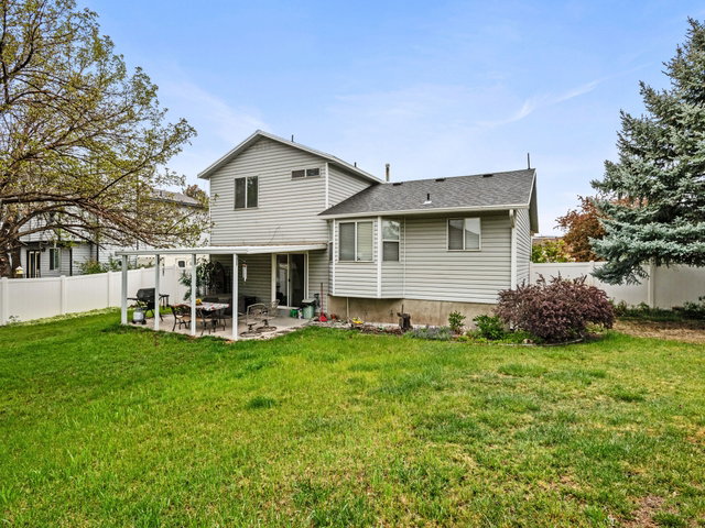 Rear view of house with a fenced backyard, a patio, and roof with shingles