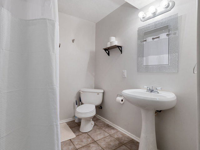 Bathroom with a shower with curtain and light tile patterned floors
