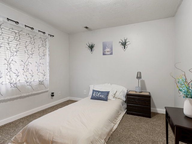 Carpeted bedroom featuring baseboards and a textured ceiling