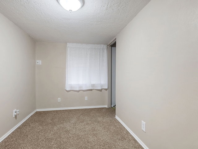 Carpeted spare room with baseboards and a textured ceiling