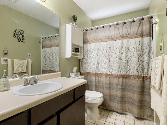 Full bath with vanity, curtained shower, and light tile patterned flooring