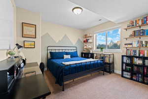 Carpeted bedroom featuring baseboards and a desk