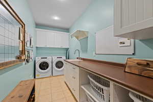 Laundry room with light tile patterned flooring, washer and dryer, and cabinet space