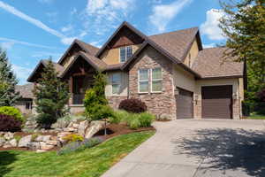 Craftsman house featuring stone siding, driveway, a garage, and stucco siding