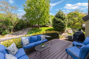 Deck with an outdoor living space, a grill, and a yard