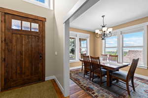Dining room with plenty of natural light, dark wood-style flooring, and suspended lighting
