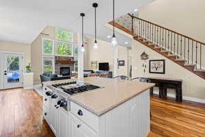 Kitchen featuring white cabinetry, a kitchen island, stainless steel gas cooktop, open floor plan, and a high ceiling