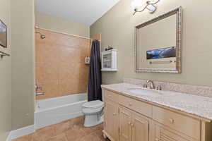 Bathroom featuring vanity, shower / bath combo with shower curtain, and light tile patterned flooring