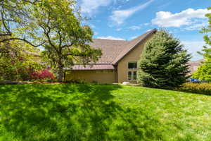 Rear view of property featuring stucco siding, a lawn, and a standing seam roof
