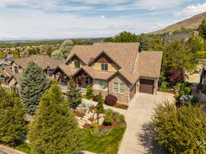 Craftsman inspired home with concrete driveway, stone siding, a porch, a mountain view, and stucco siding