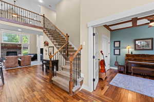 Staircase with ceiling fan, wood-type flooring, a fireplace, and a high ceiling