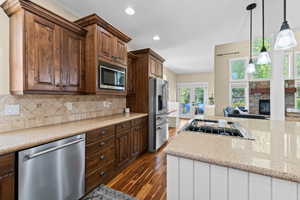 Kitchen featuring french doors, dark wood-style flooring, stainless steel appliances, light stone counters, and two tone cabinetry