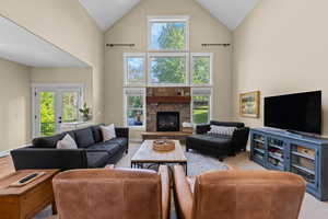 Living area with light carpet, a fireplace, lofted ceiling, healthy amount of natural light, and french doors