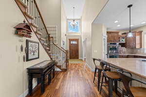 Foyer entrance featuring hanging lights, dark wood finished floors, and a high ceiling