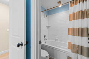 Bathroom with toilet and shower / tub combo with curtain