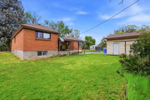 Back of house with brick siding, a lawn, and an outdoor structure